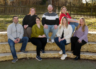 Elternbeiratsmitglieder sitzen auf Steinen im Garten