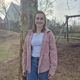 Kollegin lehnt am Baum