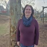 Kollegin lehnt am Baum